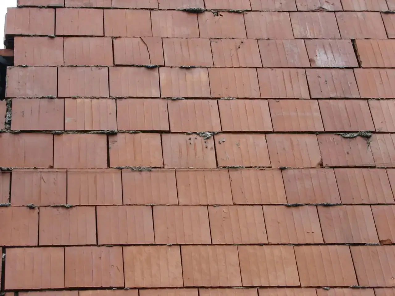 Zbliżenie na murowanie ścianek działowych z cegieł ceramicznych. Widać pionowe rowki na powierzchni cegieł i nierówności zaprawy.