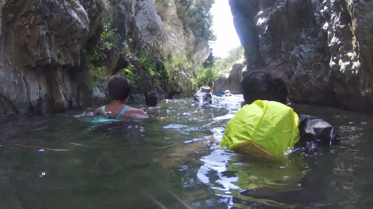 Disfrutando de la benahavis ruta rio, un grupo nada entre rocas y vegetaci&oacute;n.