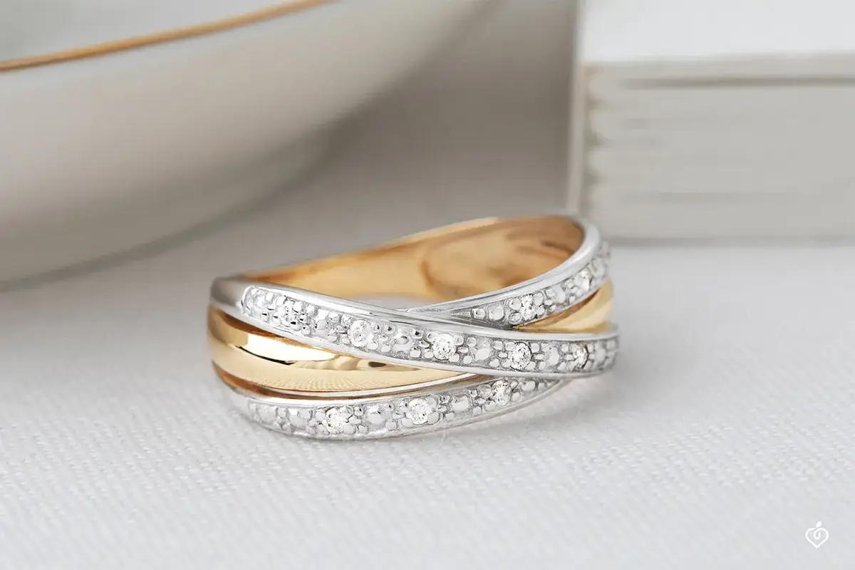 Anello intrecciato con diamanti, che mostra la differenza tra oro bianco e oro giallo.