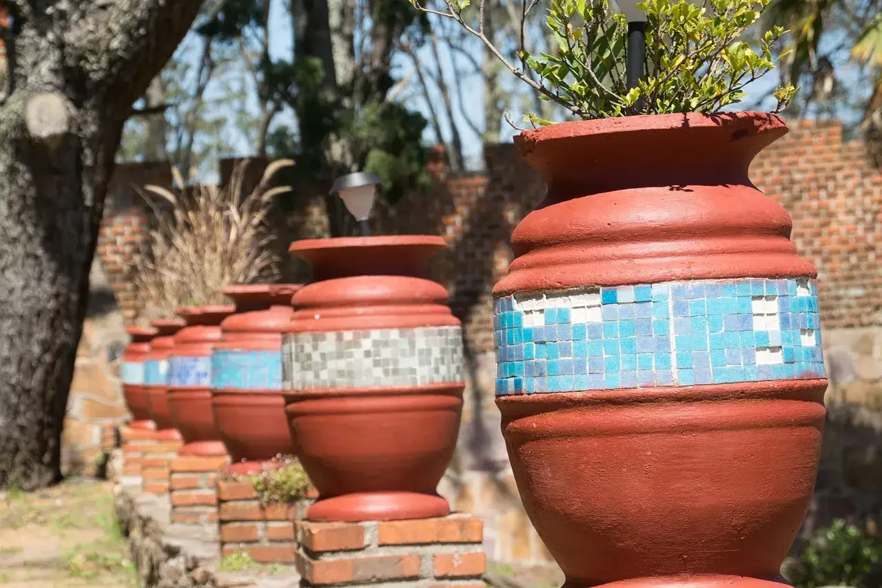 Tinajas de barro decoradas con mosaicos azules y blancos, perfectas para dar vida a tu jardín.