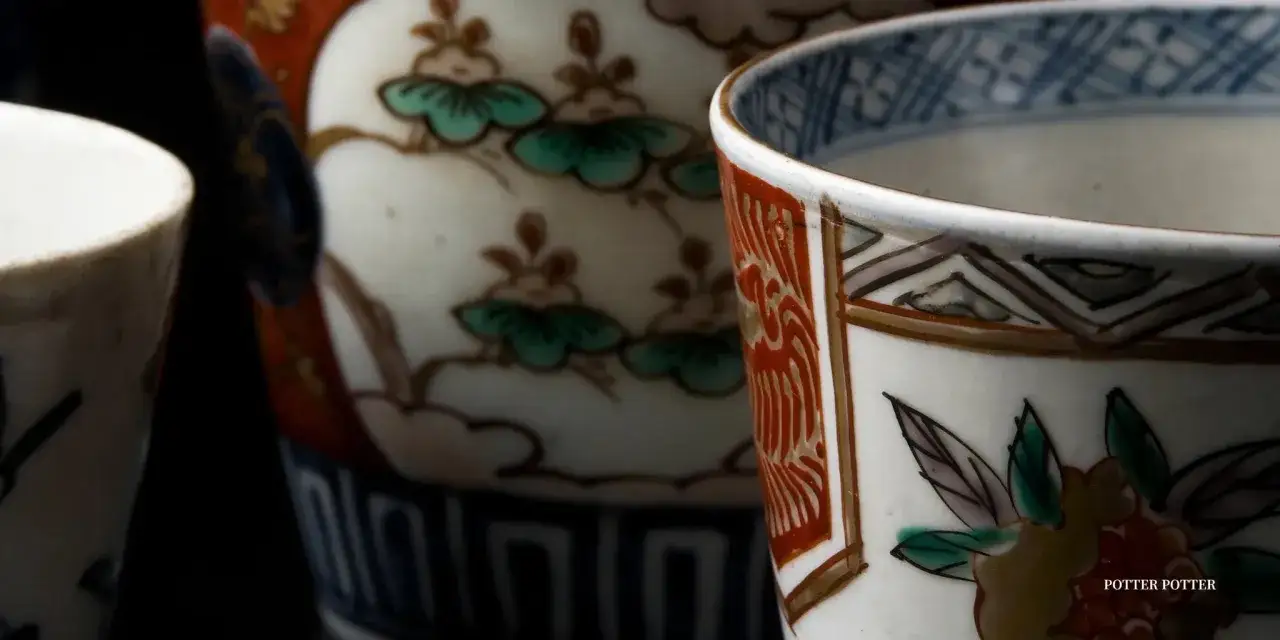 Nahaufnahme von japanischer Porzellankunst: detailreiche Tassen mit floralen Mustern und geometrischen Rändern.