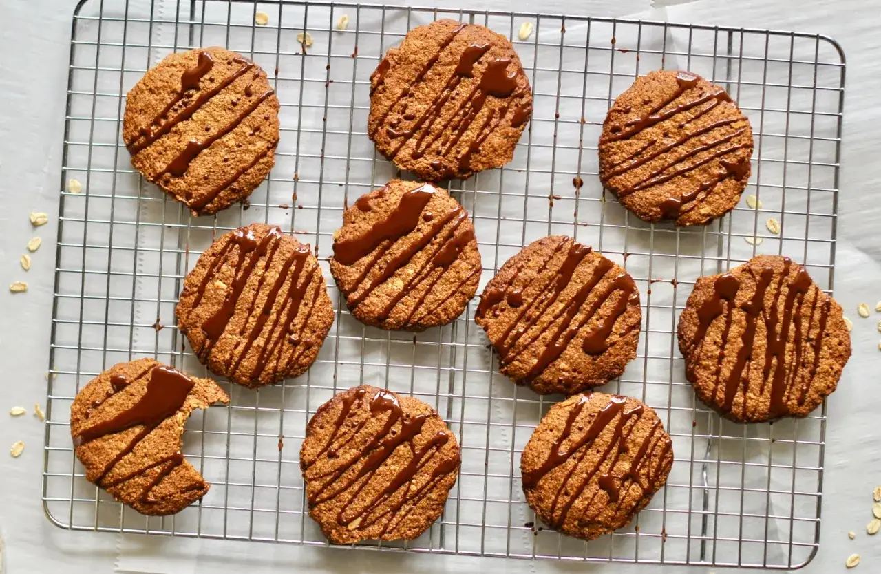 Snabba havrekakor med chokladdrizzle på ett galler. En kaka har en tugga tagen ur den.