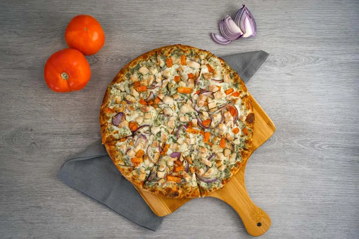 Pizza z kurczakiem i warzywami na drewnianej desce. Czy pizza jest lekkostrawna? Ta wygląda apetycznie!