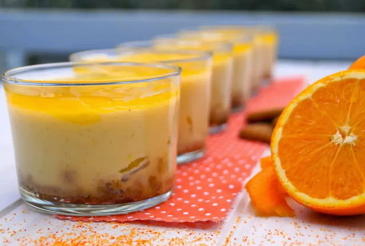 Petits verres de dessert cr&eacute;meux, surmont&eacute;s d'un coulis orange vif. Une tranche d'orange et des b&acirc;tonnets de cannelle compl&egrave;tent cette gourmandise.