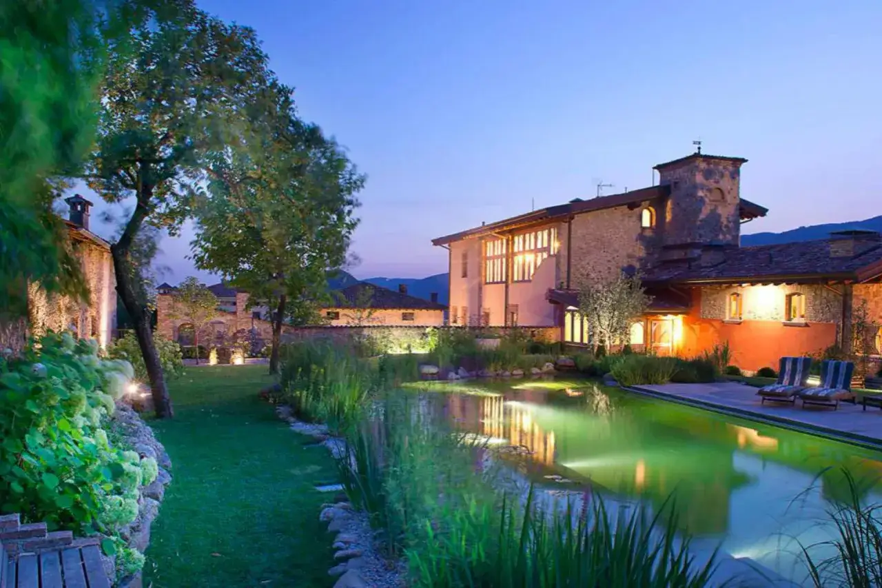 Un paisible agriturismo en Italie du Nord, avec une piscine illuminée et des bâtiments en pierre.