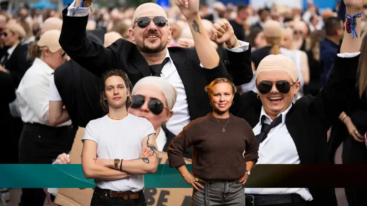 M&auml;nniskor med rakade huvuden och solglas&ouml;gon, en del med uppstr&auml;ckta armar, i en folkmassa. Framf&ouml;r syns en man i vit t-shirt och en kvinna i brun tr&ouml;ja. Kanske en demonstration i pitbull sverige.