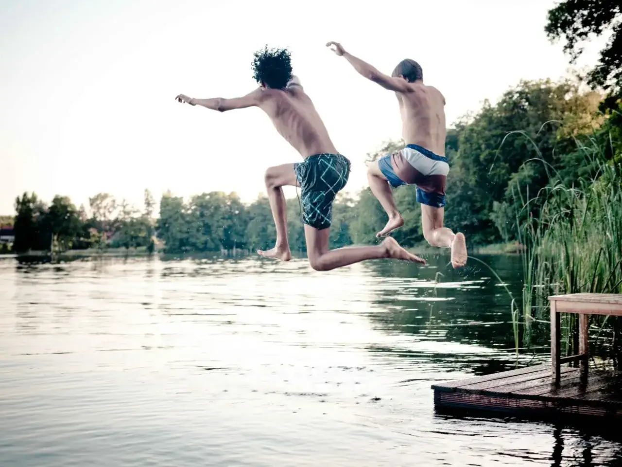 Zwei Jungen springen vom Steg in den Badesee Pforzheim. Erfrischung pur an einem sonnigen Tag.