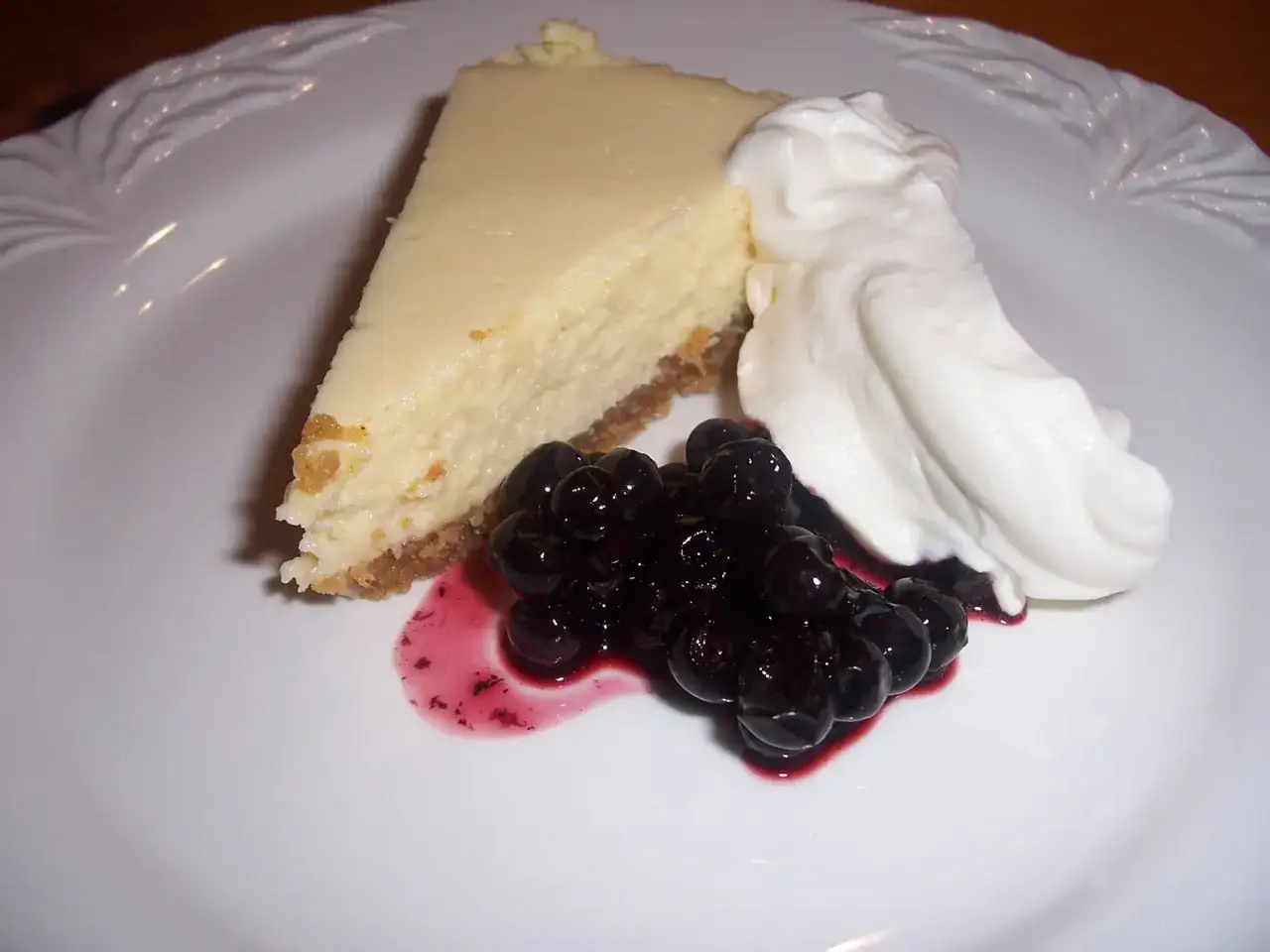 En bit kr&auml;mig key lime pie med vispgr&auml;dde och bl&aring;b&auml;r.