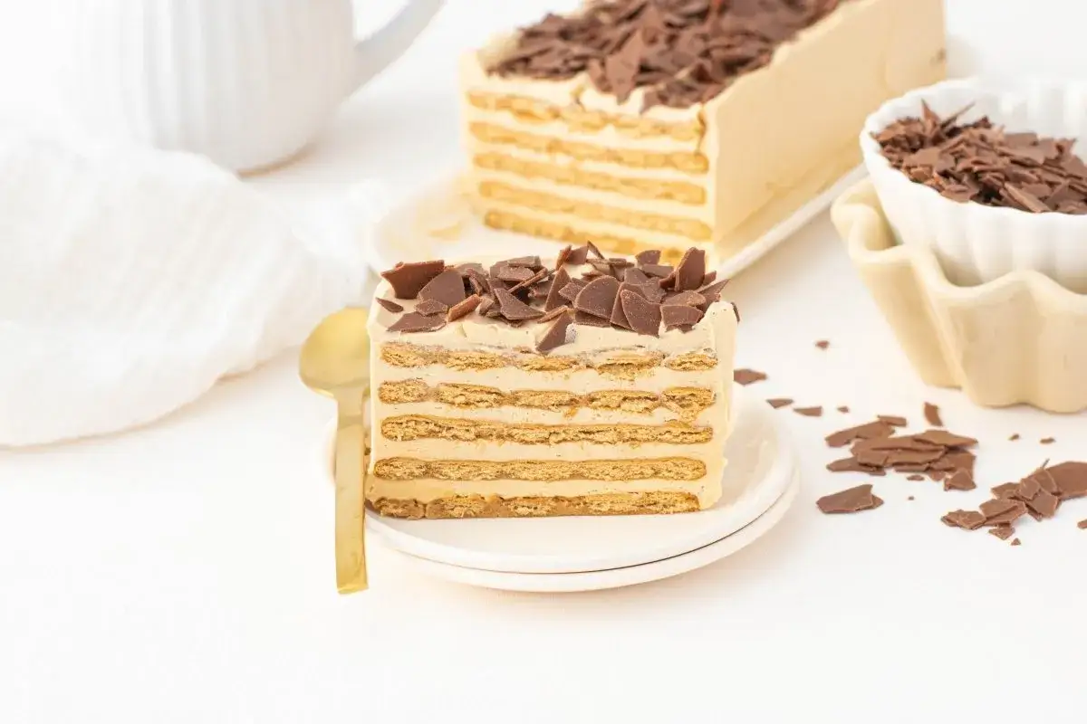 Deliciosa tarta de café con capas de galleta y crema, cubierta de virutas de chocolate.