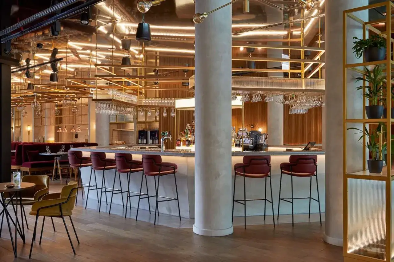 Elegancki bar w hotelu Puro Łódź z wygodnymi, czerwonymi hokerami i stylowym oświetleniem.