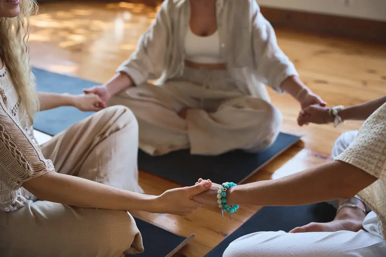People practicing positive psychology techniques, holding hands in a circle during a meditation session.
