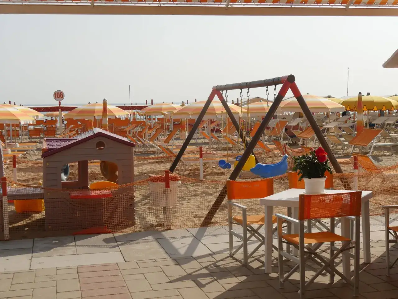 Area giochi e lettini sulla spiaggia 106 di Riccione, con altalena e casetta per bambini.