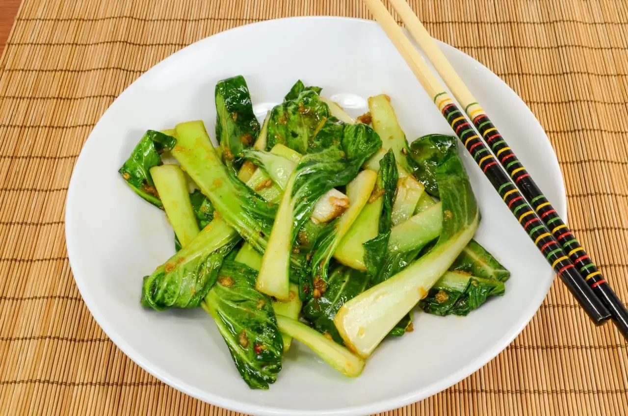 Pak cho&iuml; saut&eacute;, une recette facile et savoureuse. Servi sur une assiette blanche avec des baguettes color&eacute;es.