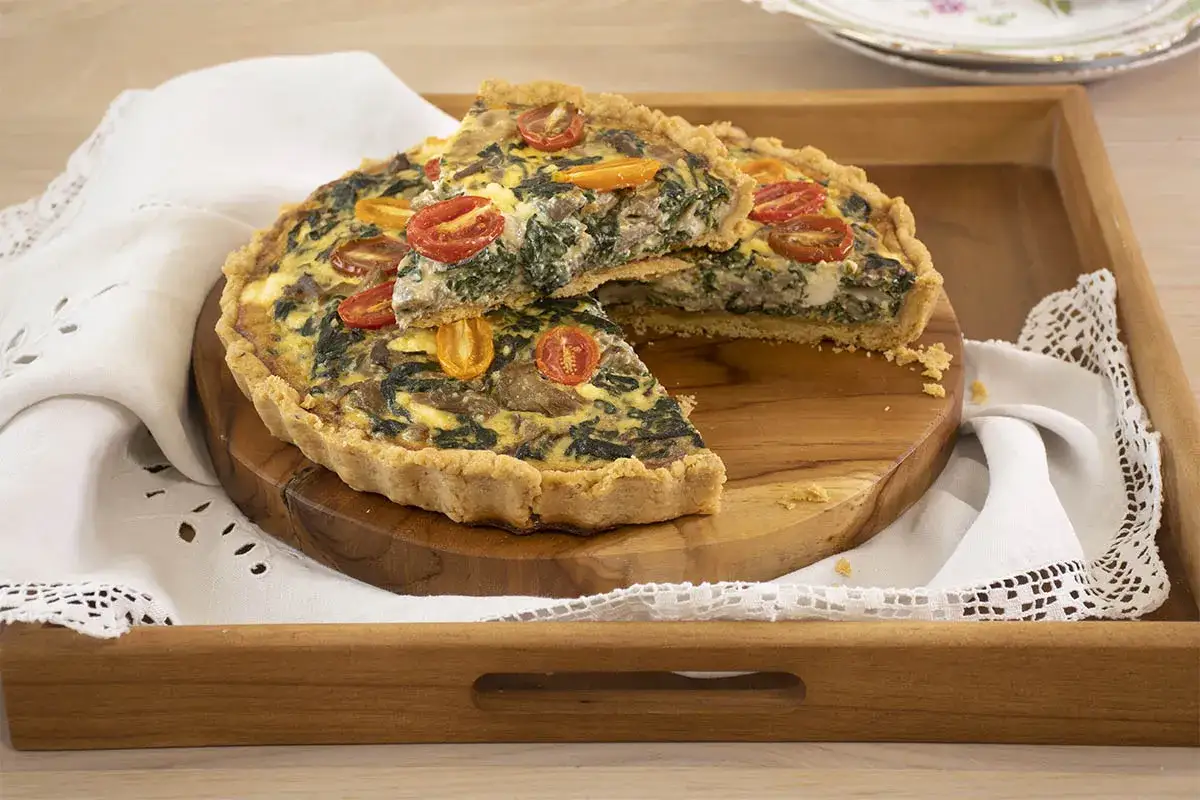 Quiche de espinacas y tomates, una de las mejores recetas con espinacas. Servida en bandeja de madera con servilleta de encaje.