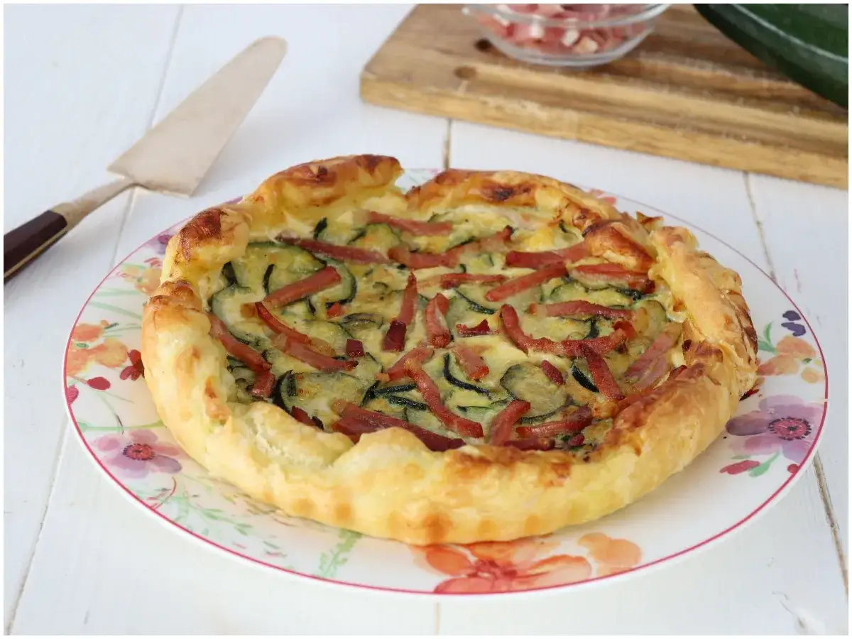 Torta salata zucchine e speck dorata e invitante, pronta per essere gustata.