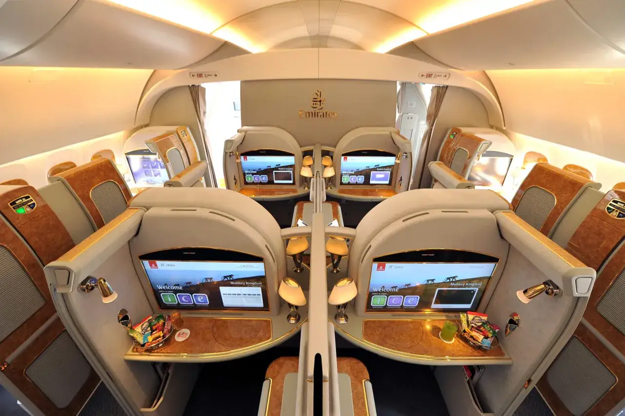 Luxuriöse Sitze in der **first class** von Emirates, mit persönlichen Bildschirmen und Snacks.