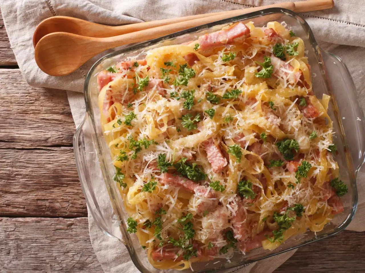 Herzhaftes Nudel Schinken Gratin, &uuml;berbacken mit K&auml;se und garniert mit Petersilie, bereit zum Servieren.