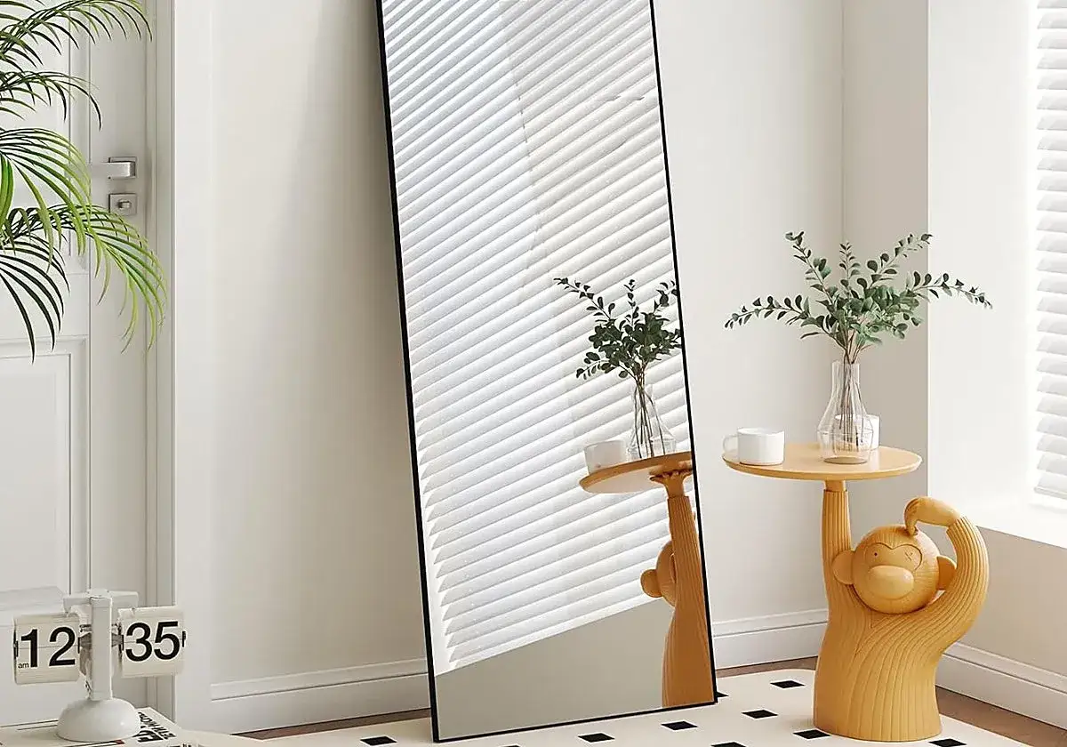 Espejo de cuerpo entero junto a una planta y una mesa auxiliar con forma de mono. Ideas de donde colocar espejos en el sal&oacute;n.