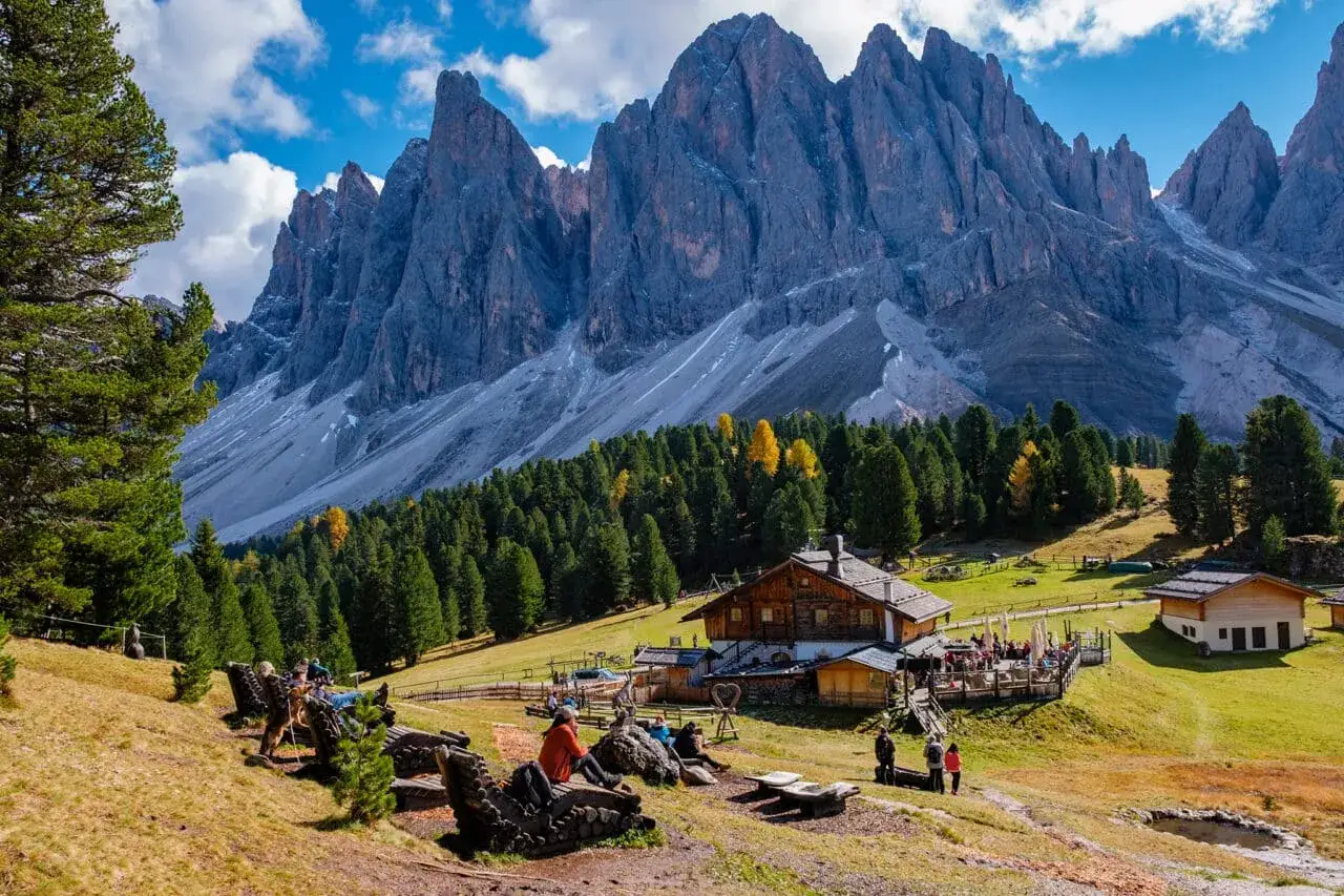 Alpenpanorama mit Berghütte und Gästen. Ein Traum für italienisches Wildcampen, mit majestätischen Gipfeln im Hintergrund.