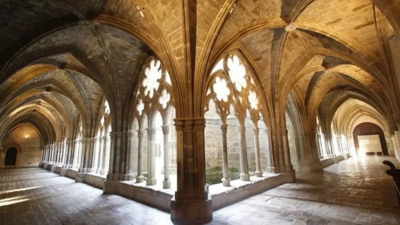 Pasillos abovedados y columnatas del **monasterio de Veruela**, con luz filtrándose por ventanales góticos.