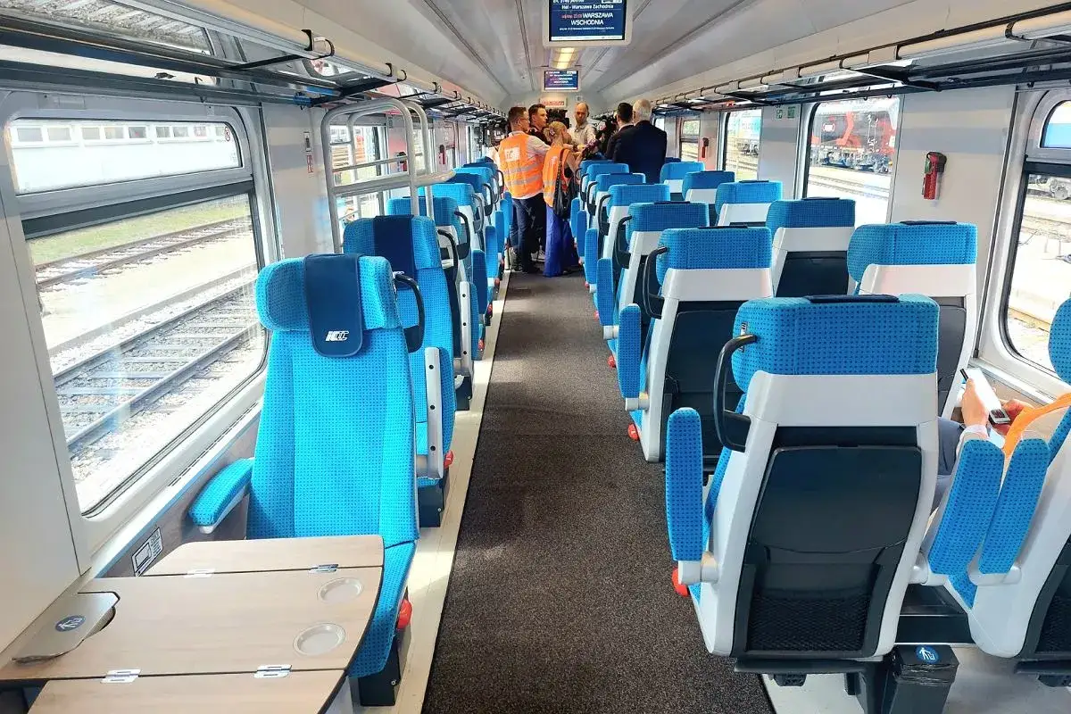 Wnętrze nowoczesnego pociągu PKP Intercity relacji Kielce-Warszawa. Jasne, wygodne siedzenia i stoliki czekają na pasażerów.