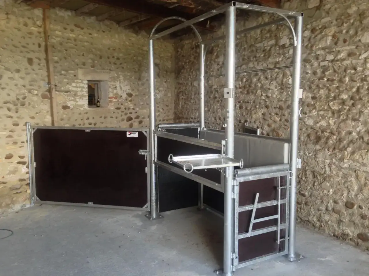 Barre d'échographie pour jument, installation métallique dans une étable en pierre.