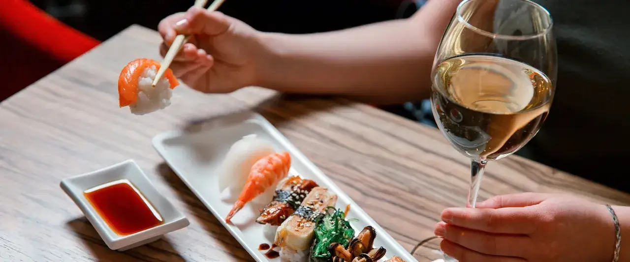 Degustacja sushi z kieliszkiem białego wina. Idealne połączenie, jeśli zastanawiasz się, jakie wino do sushi wybrać.