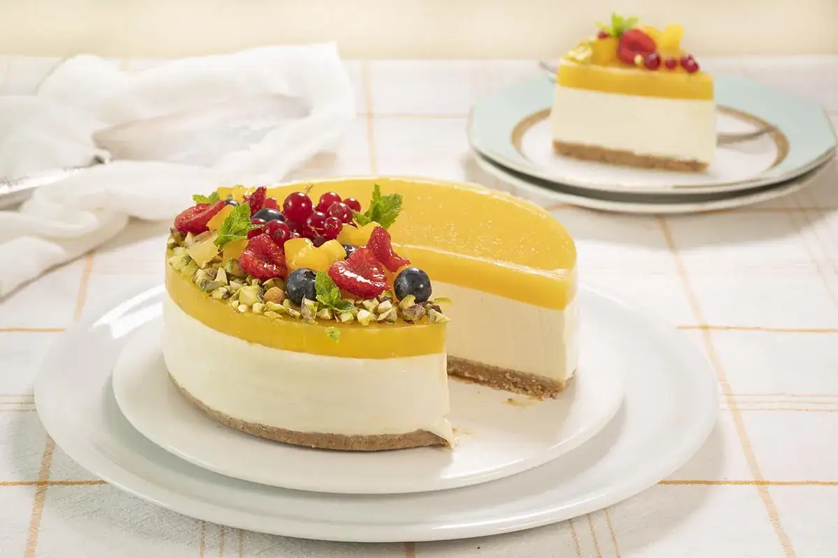 Tarta mango con frutos rojos y pistachos. Una porci&oacute;n ya cortada, lista para disfrutar.