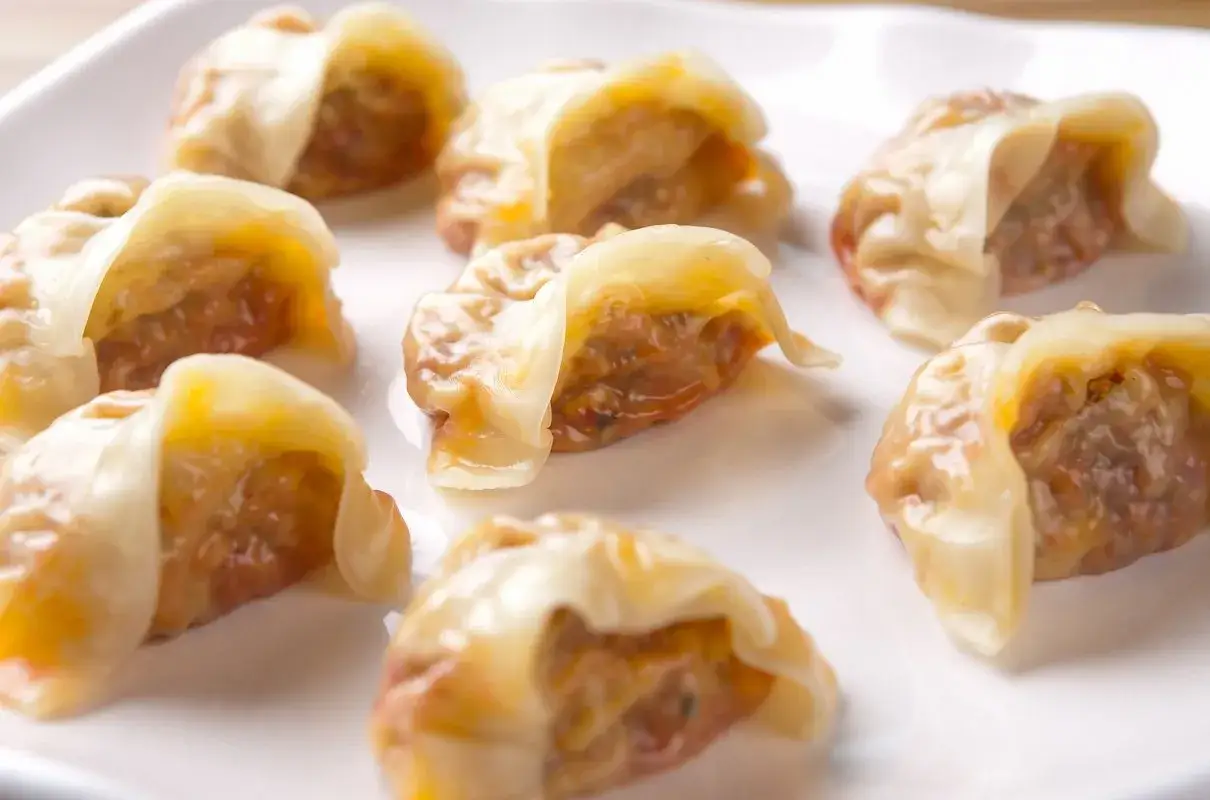 Kilka apetycznych pierog&oacute;w z kimchi ułożonych na białym talerzu.