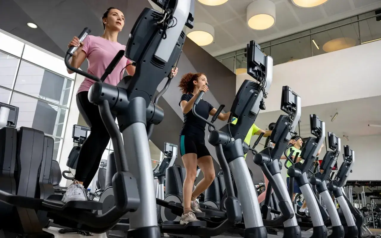 Des femmes s'entraînent sur des vélos elliptiques, profitant des nombreux vélo elliptique bienfaits pour leur forme physique.