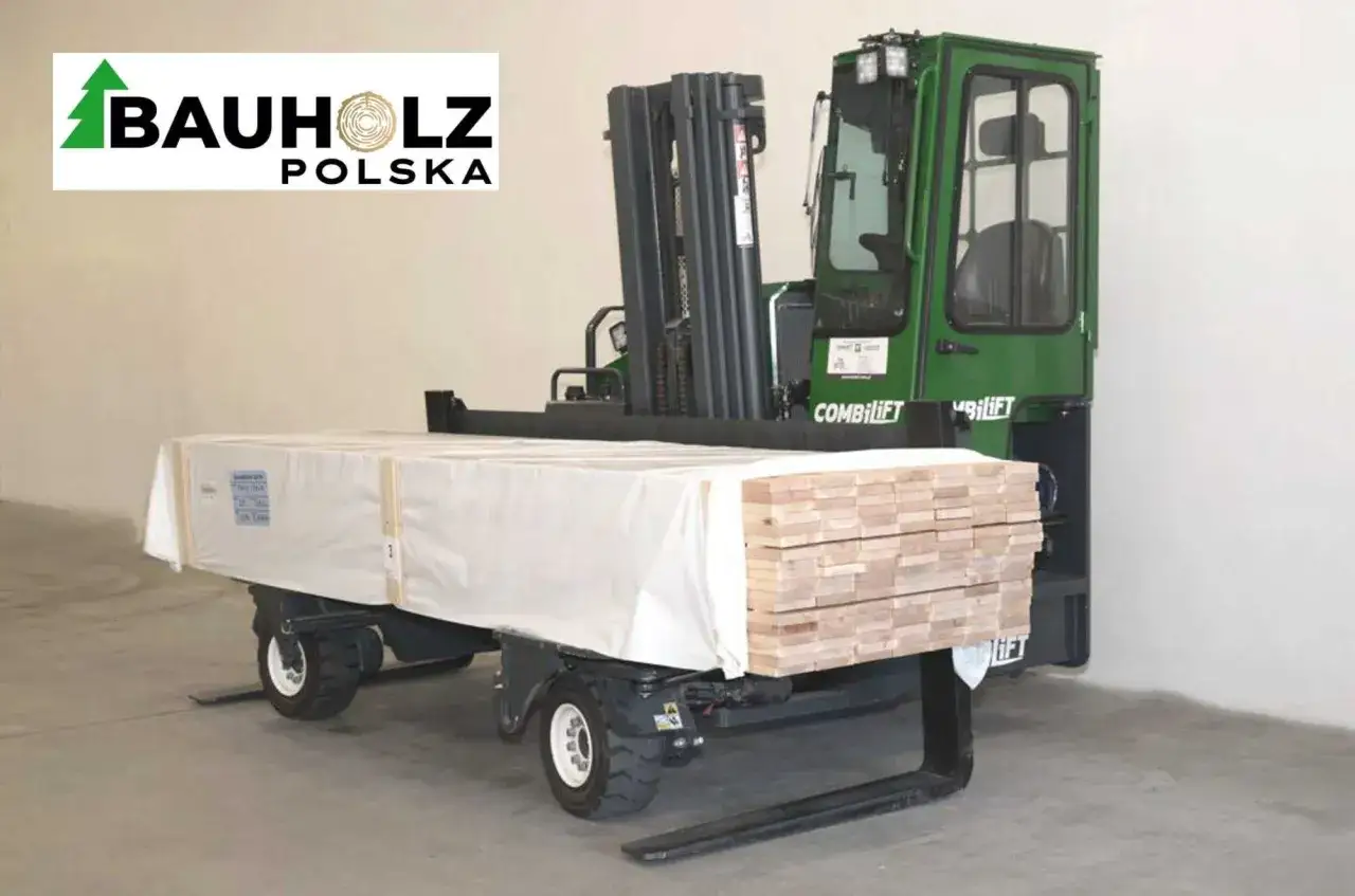 Zielony wózek widłowy Combifift przewozi drewno na dom. Pakiet drewnianych belek jest owinięty w białą folię.
