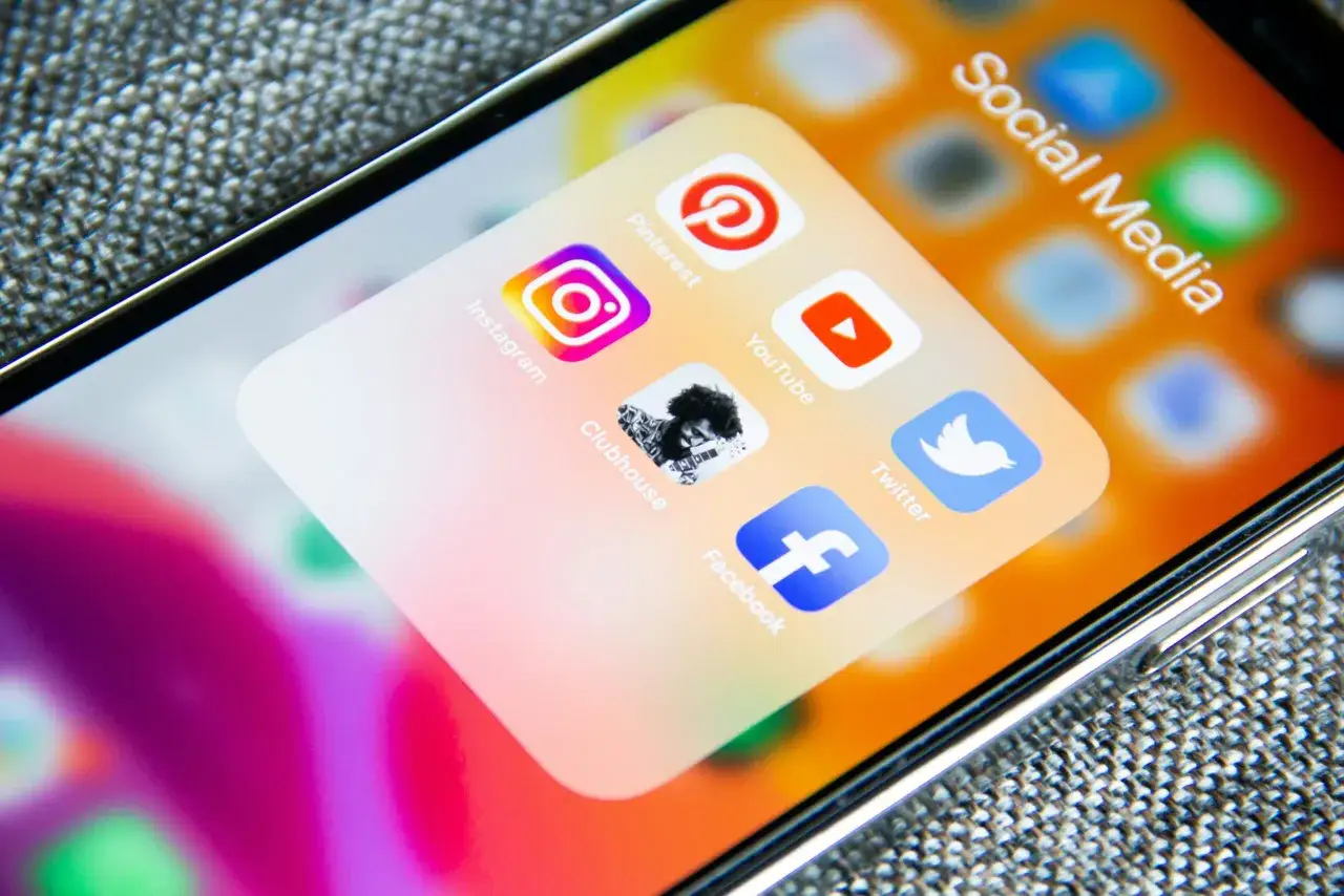 Ikona Clubhouse na ekranie telefonu, obok Instagram, Pinterest, YouTube, Twitter i Facebook. Uważaj na trolling w sieci!