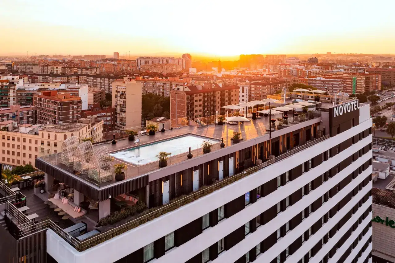 Atardecer sobre la azotea del Novotel Valencia, con piscina, tumbonas y vistas a la ciudad.