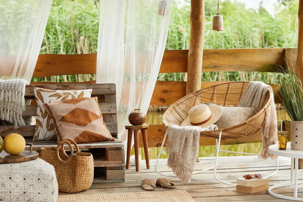 Relaks na tarasie w stylu boho: wiklinowy fotel, palety jako ławka, pleciony kosz i lniane tekstylia tworzą przytulną atmosferę.