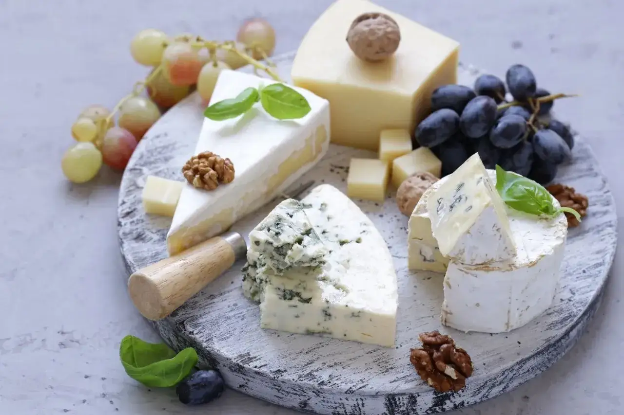 Plateau de fromages vari&eacute;s, dont du bleu et du brie, avec des raisins, des noix et du basilic. Le fromage est-il une prot&eacute;ine ? Oui, et un d&eacute;lice !