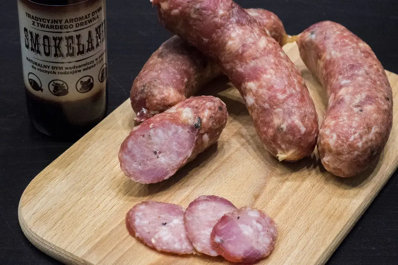Kiełbasa na desce, obok butelka z aromatem dymu. Zastanawiasz się, ile czosnku do kiełbasy?