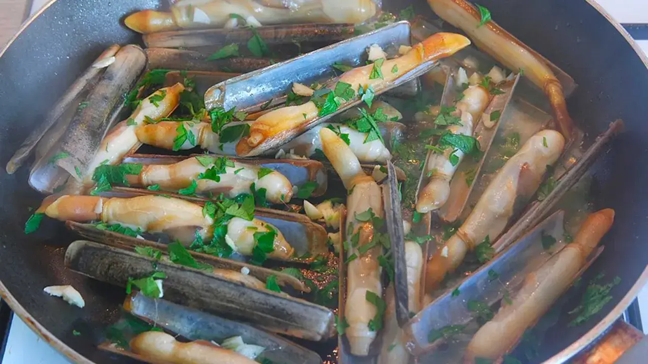 Couteaux en persillade cuits dans une po&ecirc;le, parsem&eacute;s de persil frais. Un plat savoureux pr&ecirc;t &agrave; &ecirc;tre d&eacute;gust&eacute;.