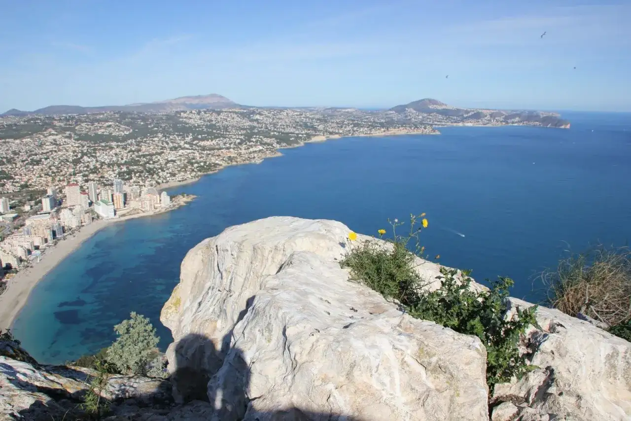 Widok na wybrzeże Alicante w grudniu. Błękitne morze, plaża i miasto pod błękitnym niebem.