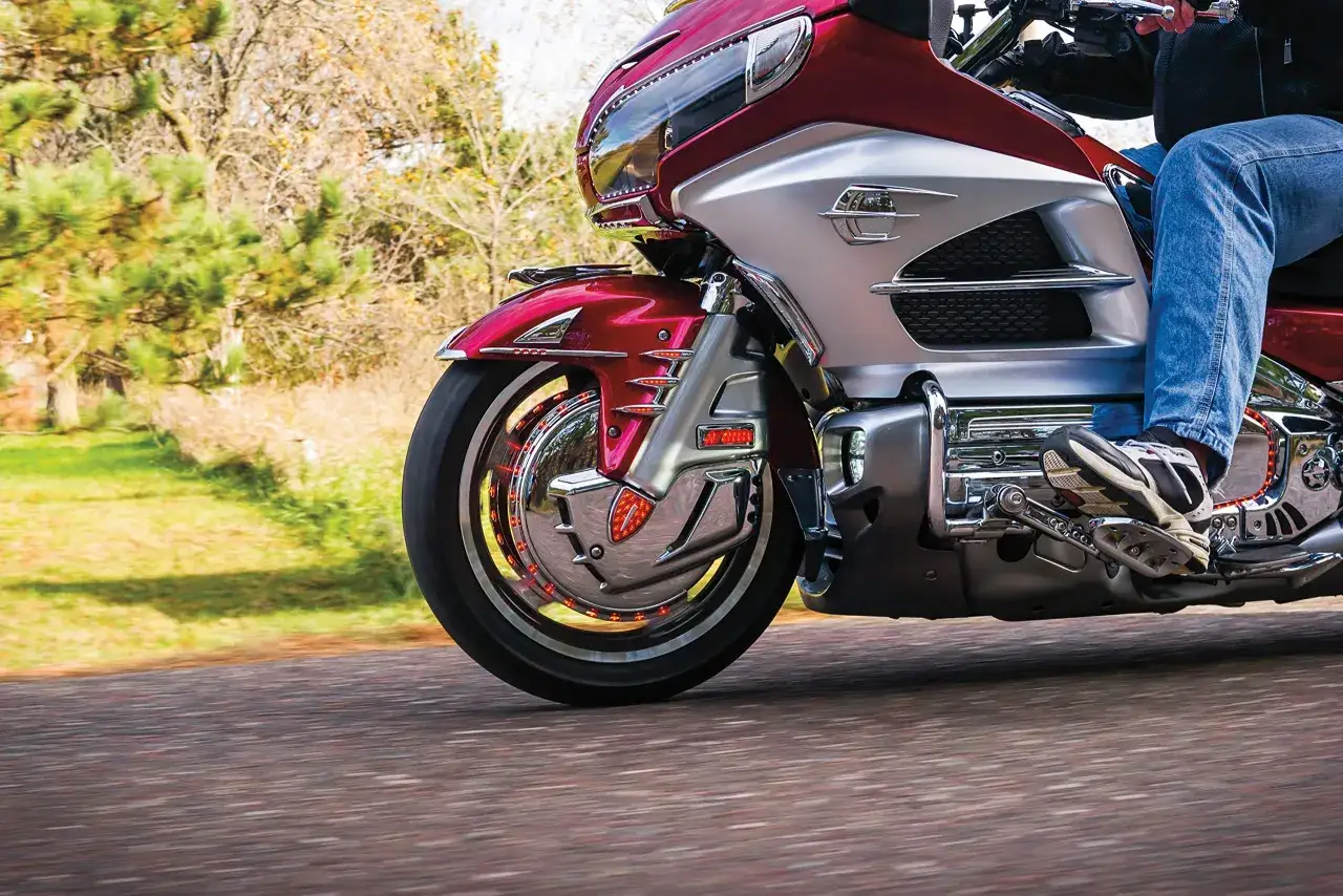 Honda Goldwing 1800 z błyszczącymi akcesoriami chromowanymi, mknąca po drodze wśr&oacute;d jesiennej zieleni.
