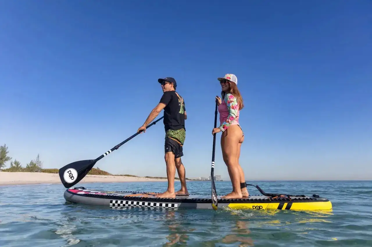 Para na desce SUP, czyli stand up paddleboarding, to świetna zabawa. On i ona cieszą się słońcem i wodą.