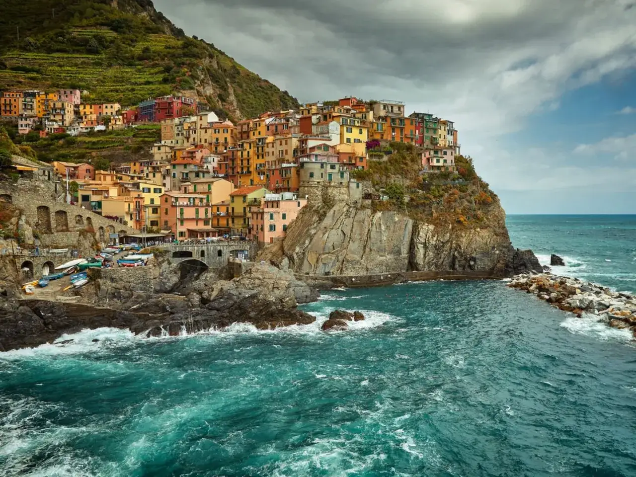 Bunte H&auml;user kleben an steilen Klippen in Cinque Terre, Italien. Das t&uuml;rkisfarbene Meer bricht sich an den Felsen.