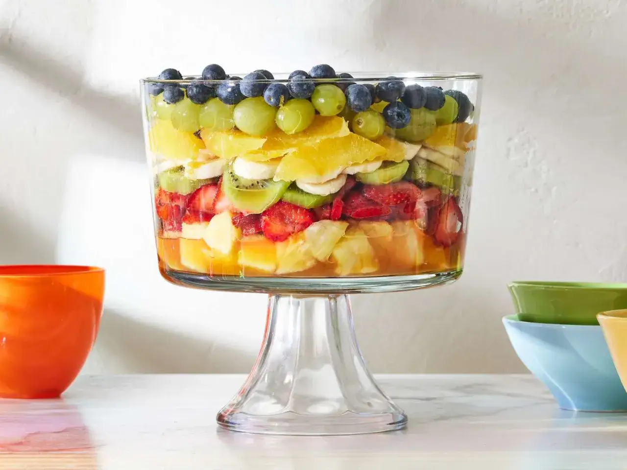 Un grand trifle de salade de fruits été, avec des couches de fraises, kiwis, bananes, oranges, raisins et myrtilles.