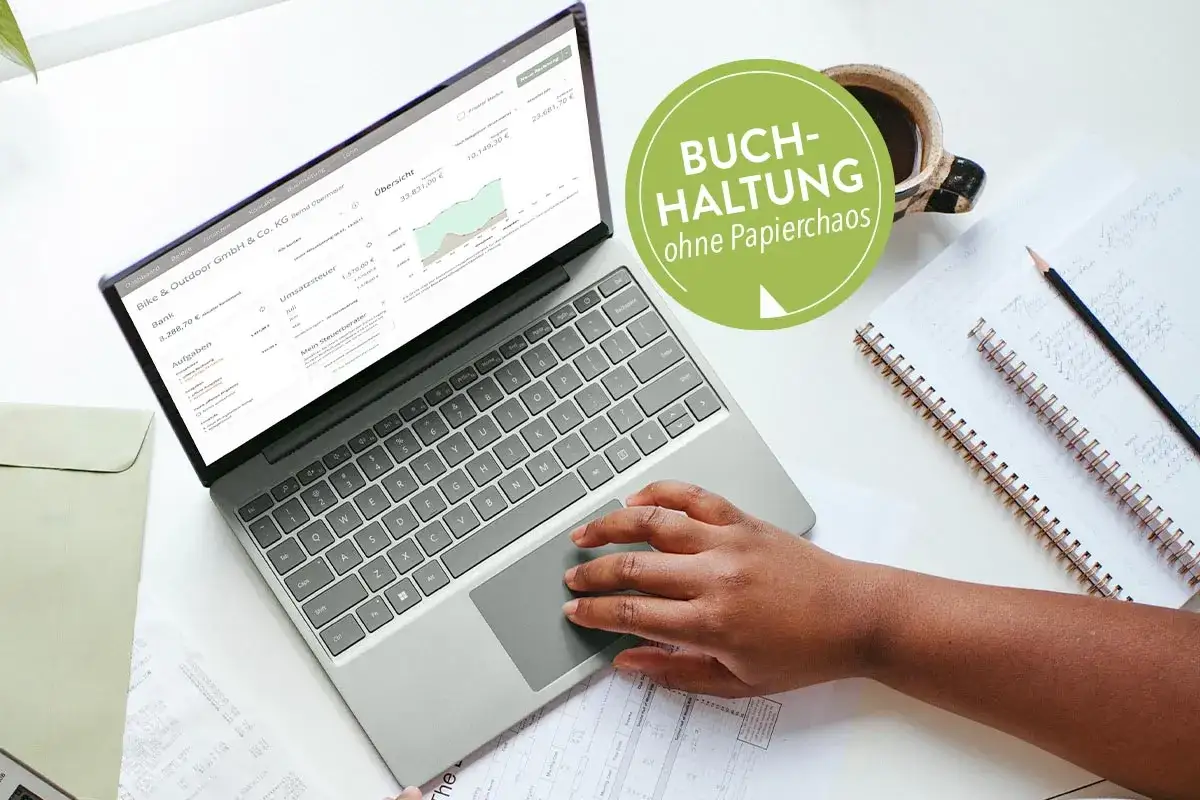 Laptop mit Buchhaltungssoftware, Kaffee und Notizbuch. Ideal für einen Fernkurs Buchhaltung.