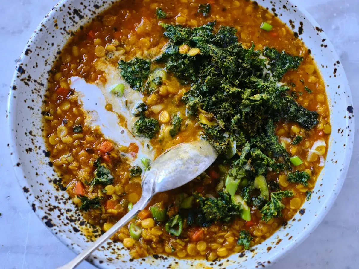 Herzhafte rote Linsensuppe mit Kokosmilch, garniert mit Grünkohl und Frühlingszwiebeln. Eine cremige, wärmende Mahlzeit.