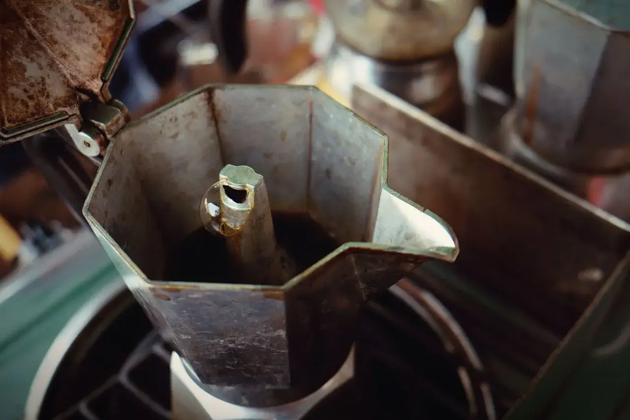 Moka sporca con residui di caffè e un po' di muffa. La moka è aperta, mostrando l'interno metallico e il caffè scuro.