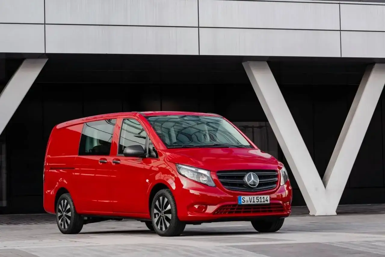 R&ouml;d Mercedes Vito st&aring;r parkerad framf&ouml;r en modern byggnad. Inga problem syns med bilen.