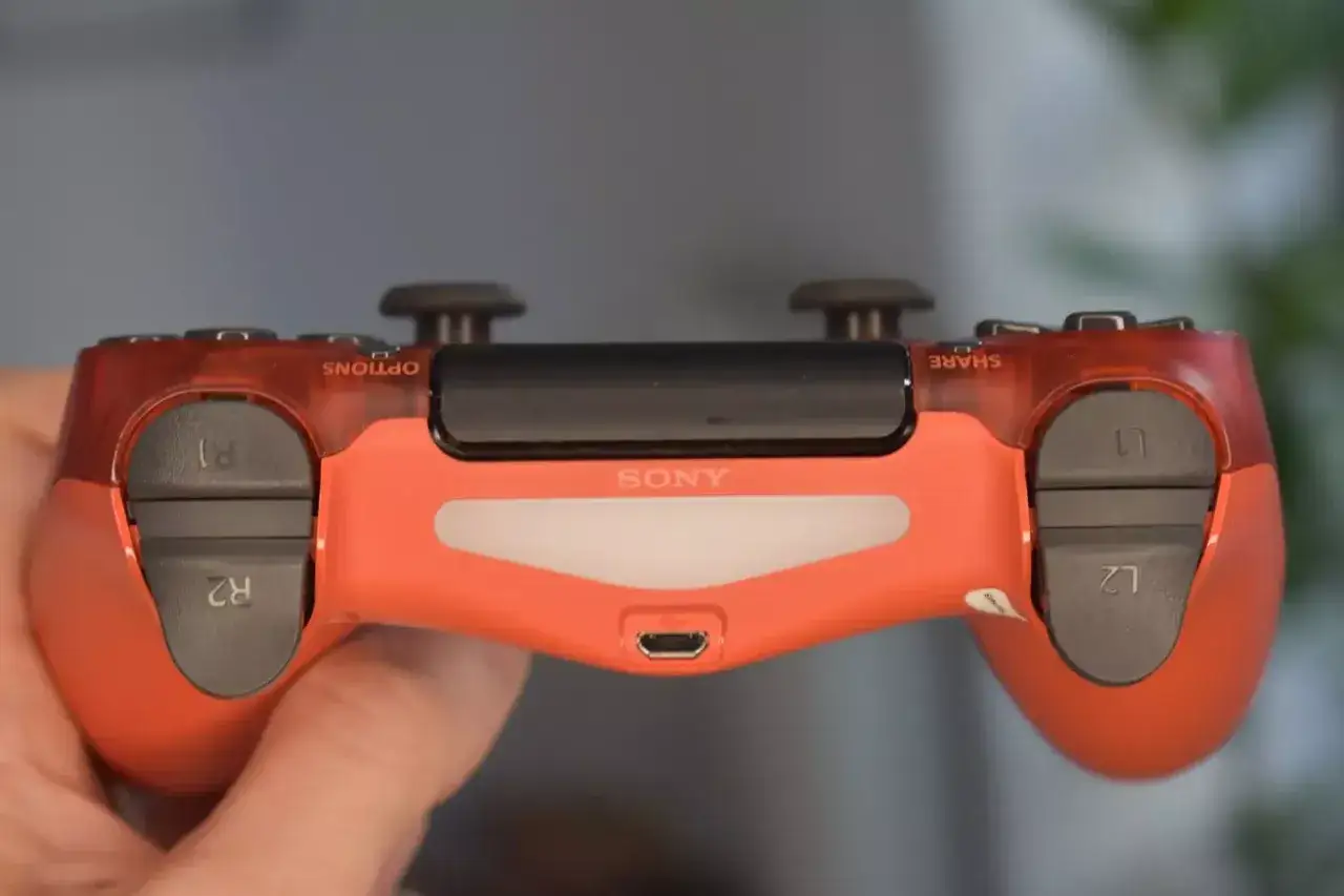 Czerwony pad od PS4 w dłoni. Czy pad od PS4 pasuje do PS5? Sprawdźmy!
