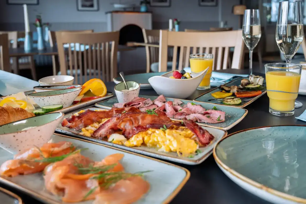 Üppiger Brunch in Schleswig-Holstein: Rührei, Speck, Lachs, Aufschnitt, Obst und Orangensaft laden zum Genießen ein.