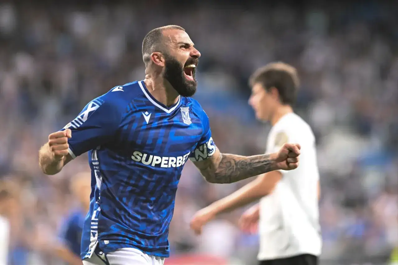 Mikael Ishak w niebieskiej koszulce Lecha Poznań świętuje gola, krzycząc z radości.