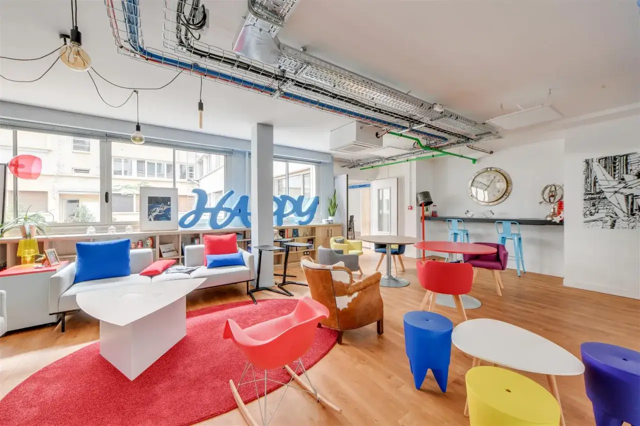 Ambiance conviviale dans ces nouveaux bureaux avec canap&eacute;s confortables, tables color&eacute;es et un grand 